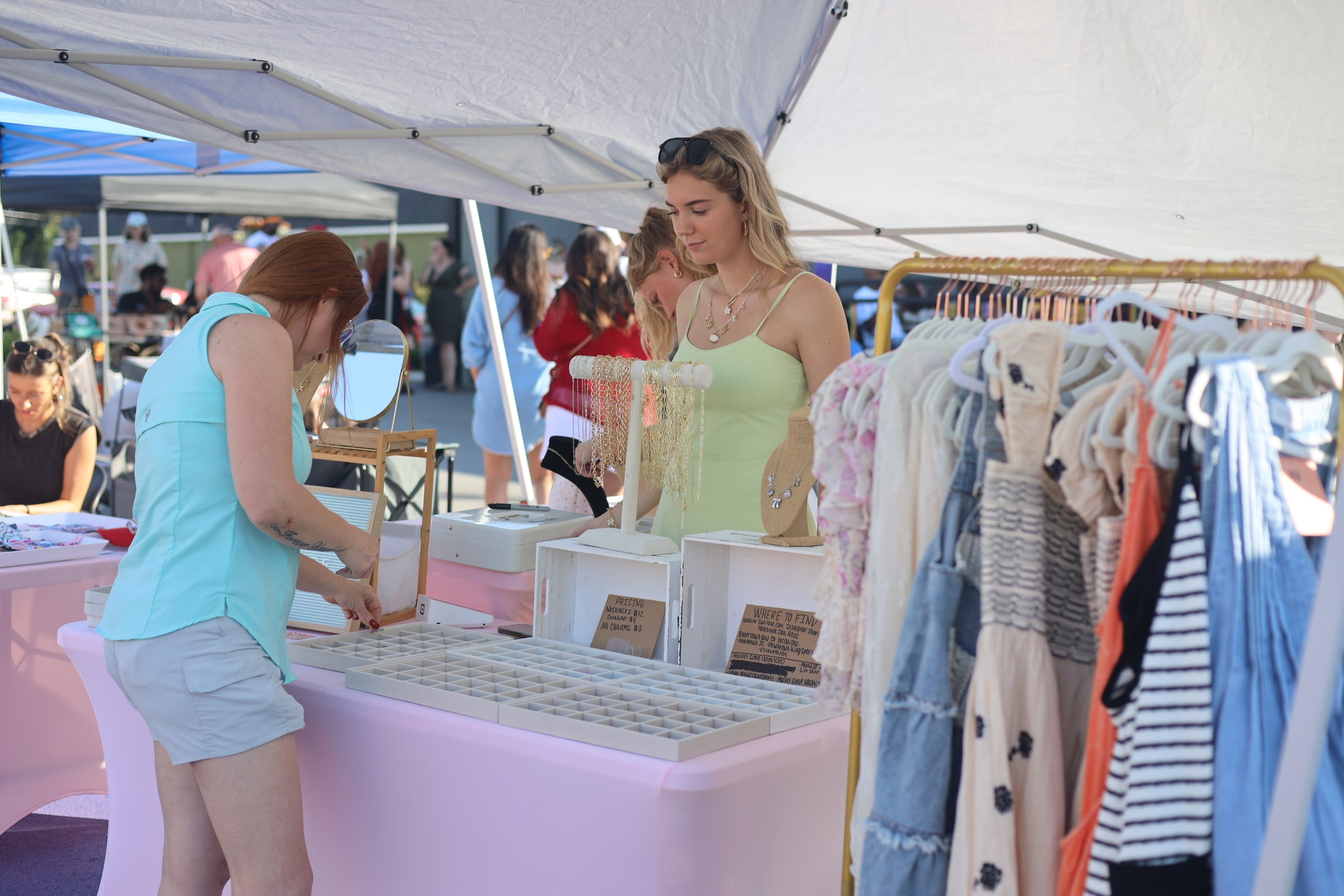 Two women at a market stall with clothing on display