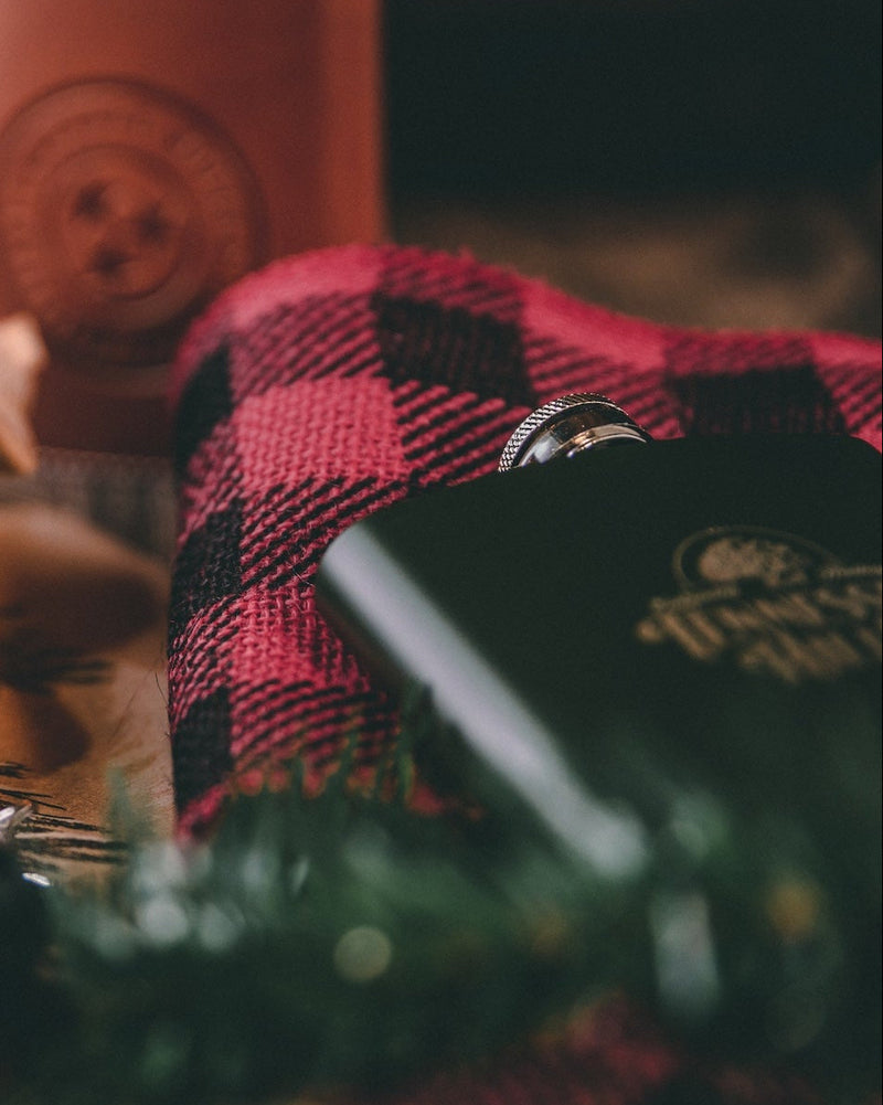 Brown leather wallet with TN Hills logo on a wooden surface with blurred Christmas tree and lights in the background.
